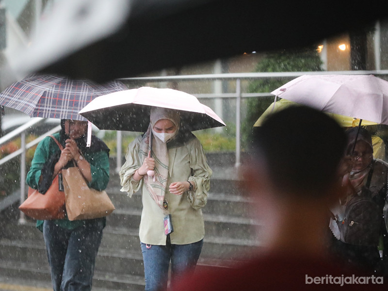 Warga menggunakan payung di tengah guyuran hujan