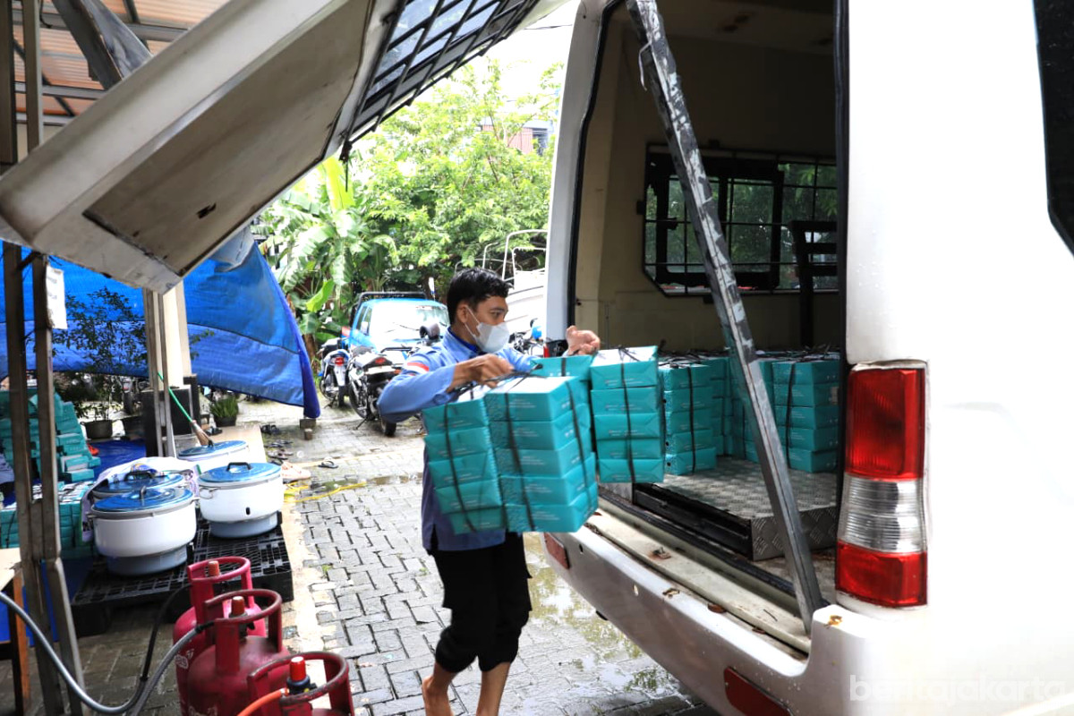 Petugas memasukan kotak makanan yang akan didistribusikan kepada penyintas genangan di Jaksel