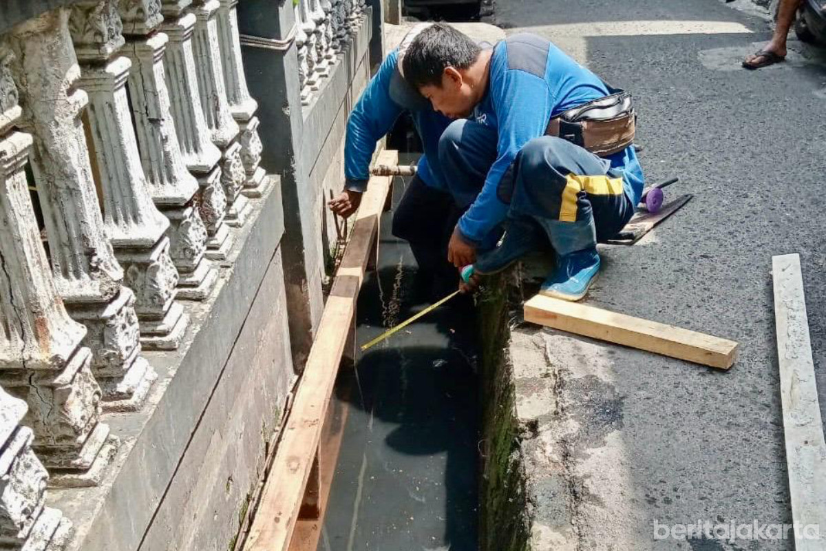 Petugas melakukan pengukuran sebelum memasang tutup saluran di Jl Bahari V