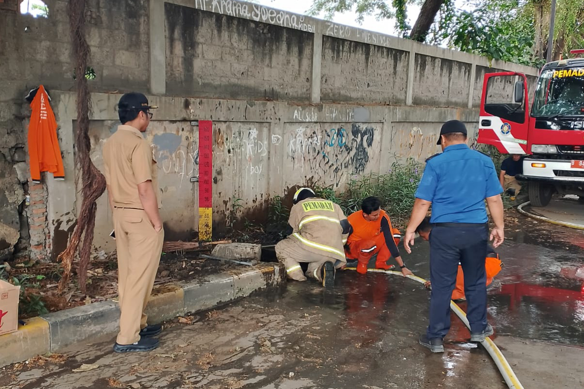 Proses penyemprotan sedimen oleh petugas Damkar dibantu PPSU