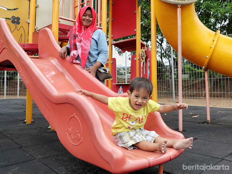 Seorang ibu mendampingi anaknya saat bermain perosotan di RPTRA
