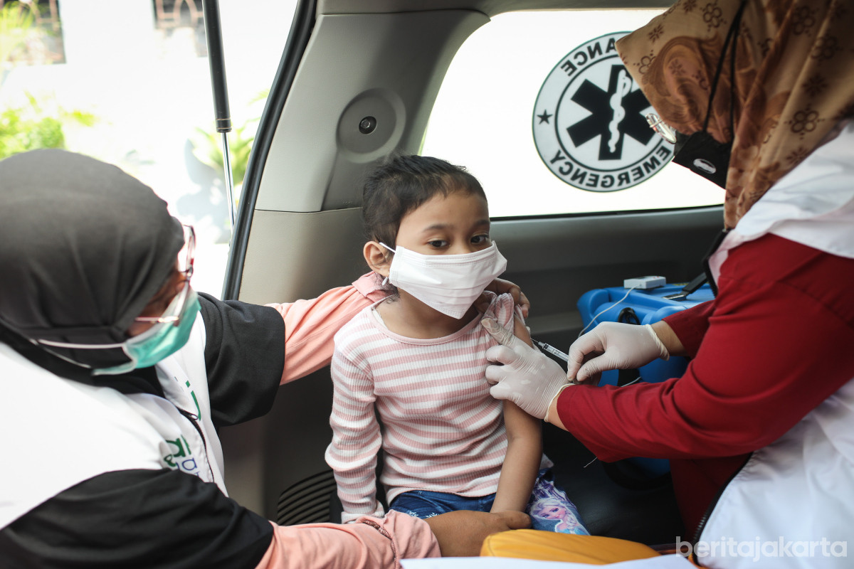 Petugas menyuntikkan vaksin campak kepada seorang anak