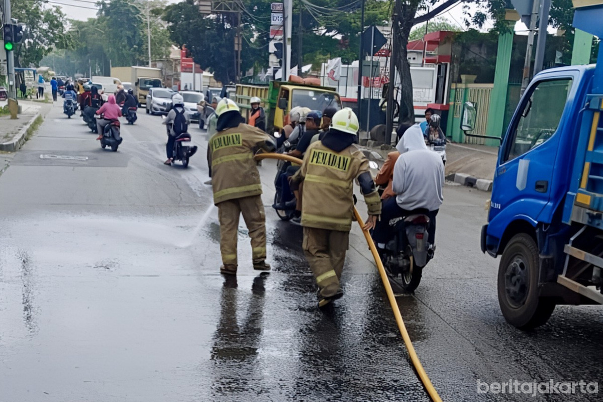 Petugas Gulkarmat membersihkan tumbahan oli di jalan