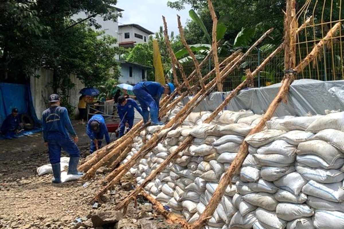 Sejumlah petugas melakukan perbaikan tanggul sementara di Pulo Raya