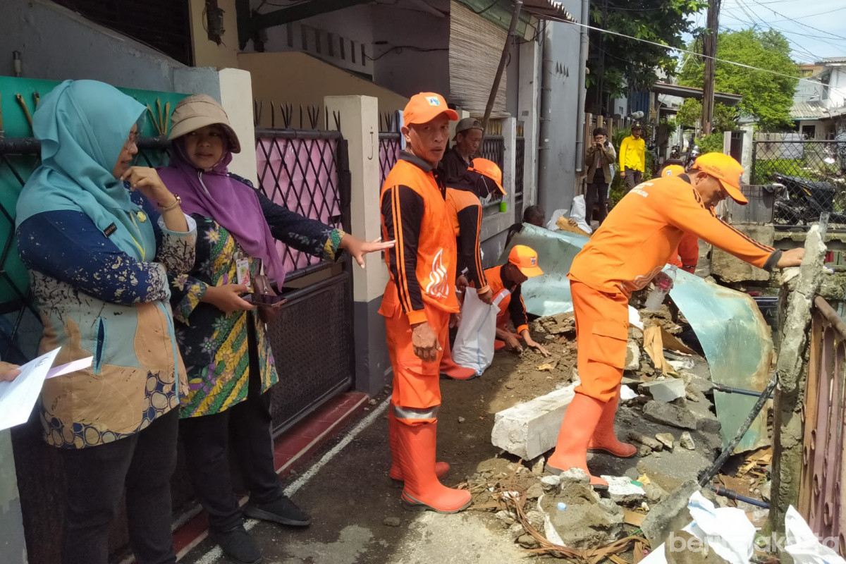 Petugas PPSU membersihkan puing dua jembatan ambruk di Utan Kayu Selatan 