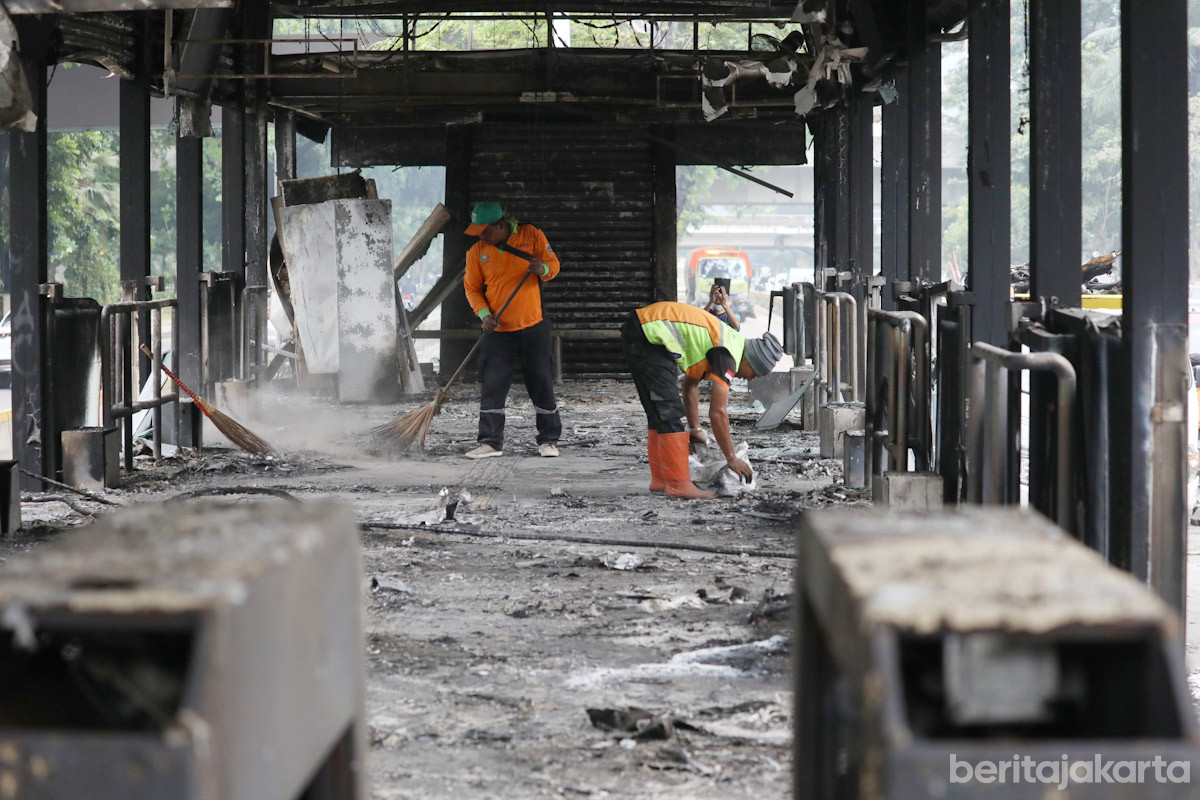 Petugas membersihkan puing sisa pembakaran Halte Transjakarta Polda Metro Jaya, Jakarta Selatan