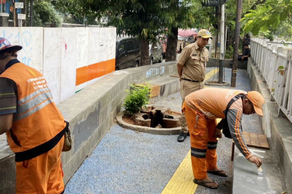 Petugas PPSU kelurahan Kartini sedang membersihkan coret-coretan di jalan dan tembok