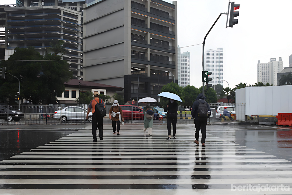 Warga menyeberangi jalan saat cuaca hujan