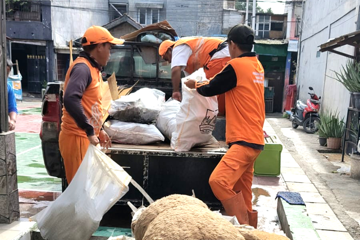 Petugas PPSU membersihkan puing atap rumah terbang di Pondok Kopi