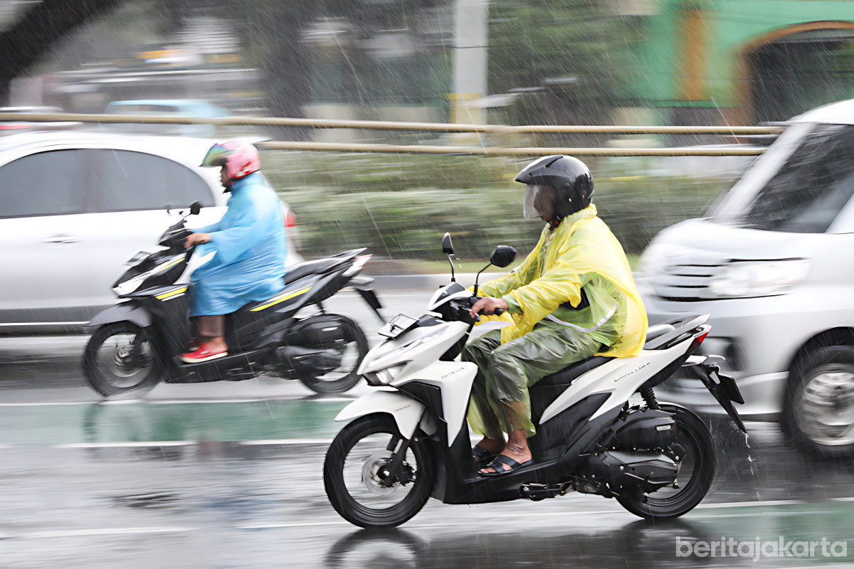 Pengendara sepeda motor melintas di tengah guyuran hujan