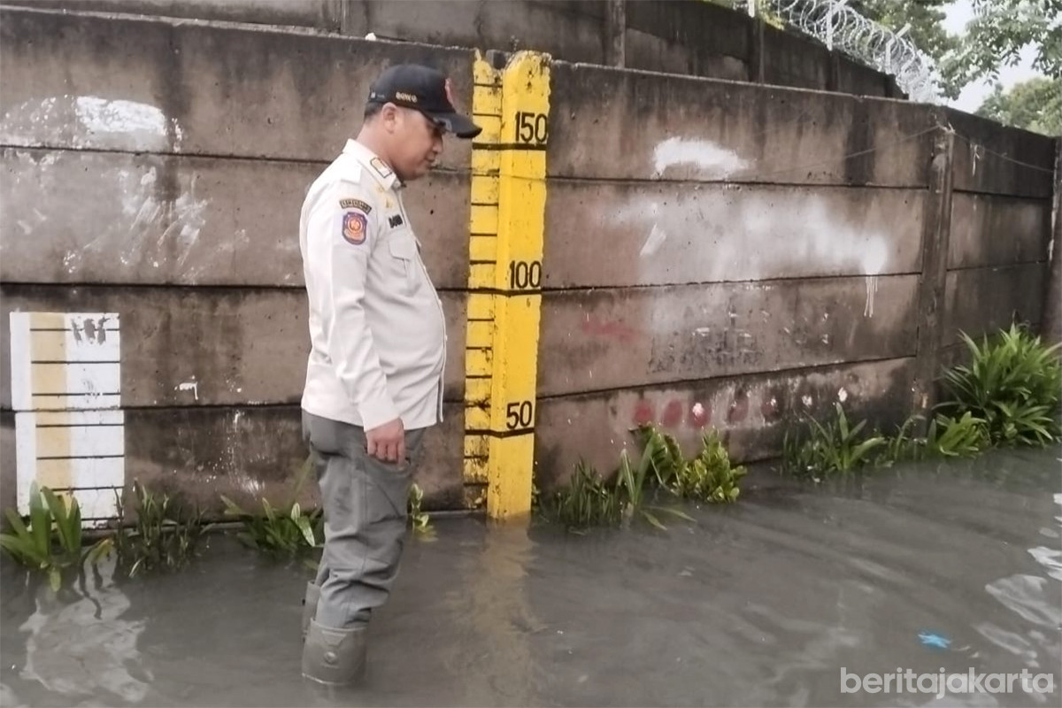 Petugas Satpol PP memantau tinggi genangan di RW 05 Rawa Terate
