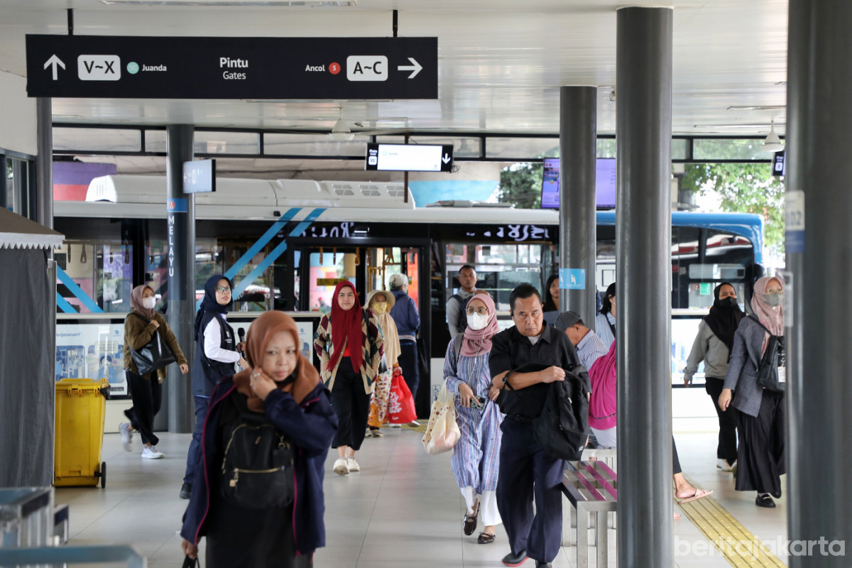 Sejumlah penumpang menuruni bus dan berjalan keluar halte Transjakarta