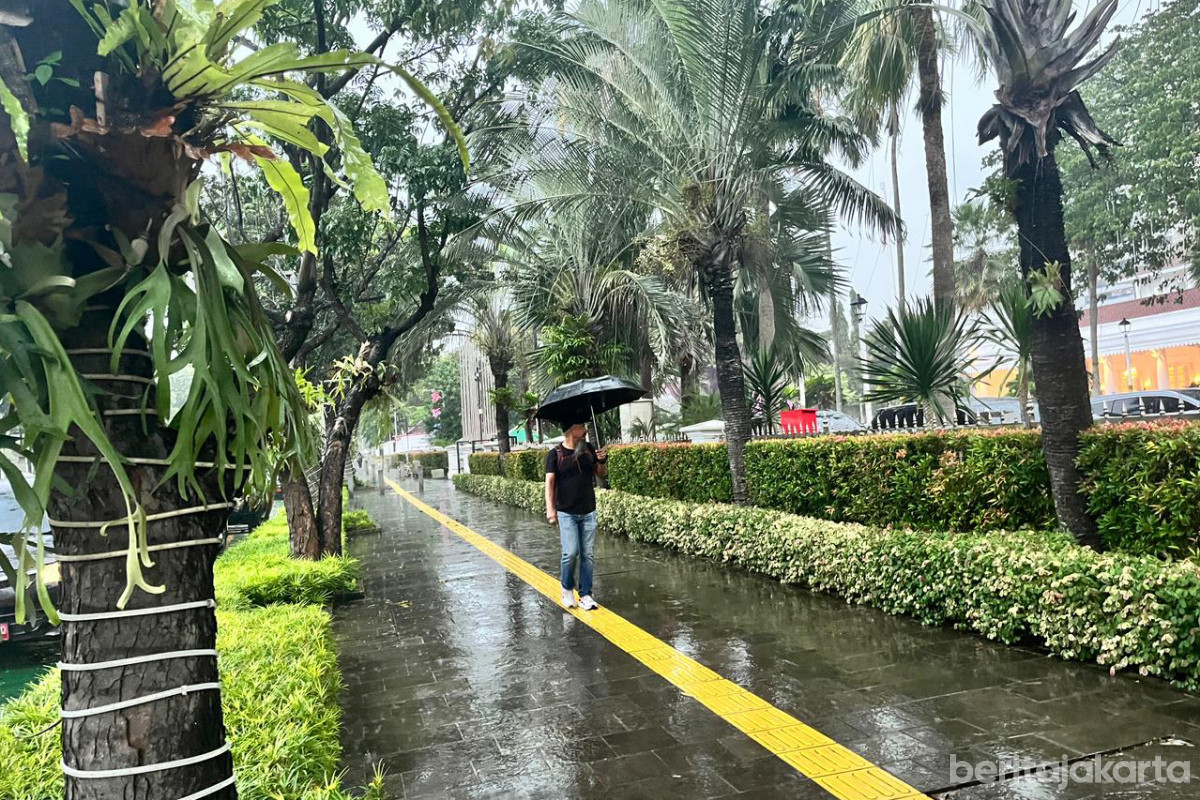 Seorang warga menggunakan payung ketika hujan basahi Jakarta