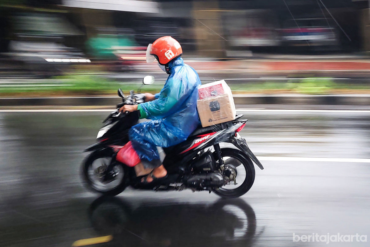 Pengendara motor melintas saat cuaca hujan