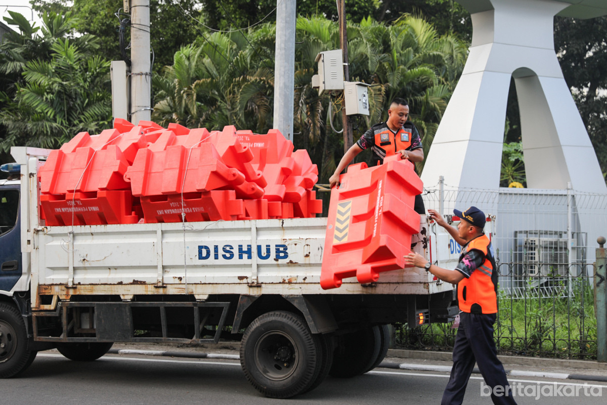 Petugas menurunkan pembatas jalan untuk rekayasa lalu lintas
