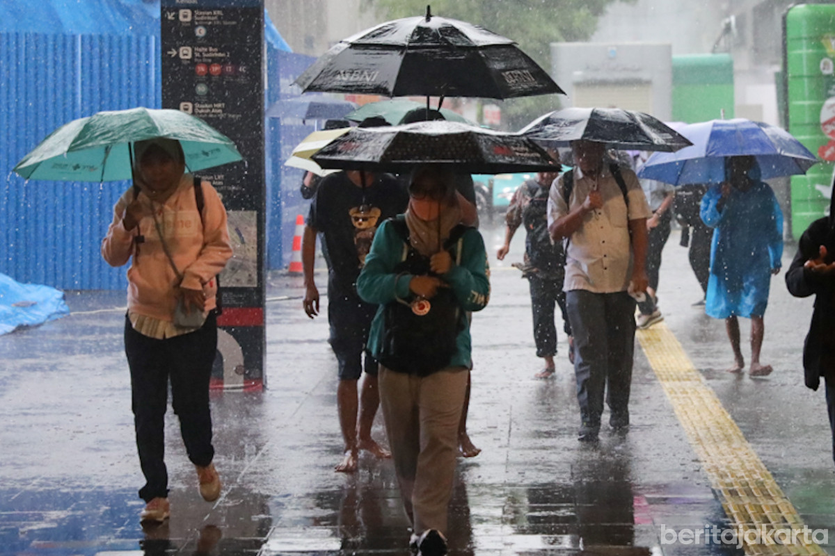 Sejumlah warga berjalan menggunakan payung di gedung perkantoran