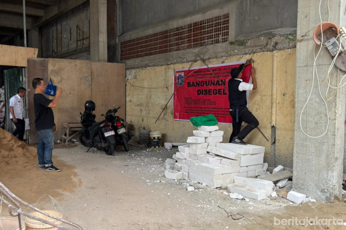 Petugas memasang spanduk segel pada bangunan rumah yang melanggar perizinan