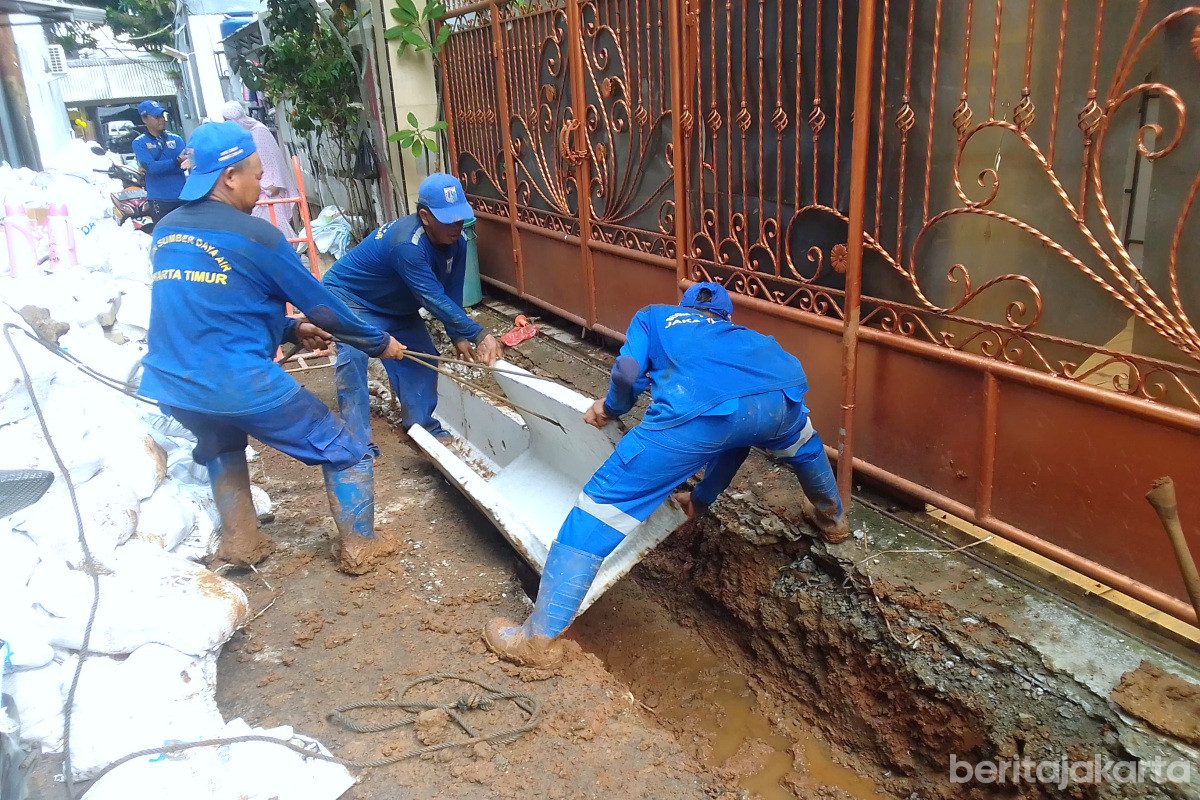 Proses pemasangan beton u-ditch ke dalam saluran air di Kelapa Dua Wetan