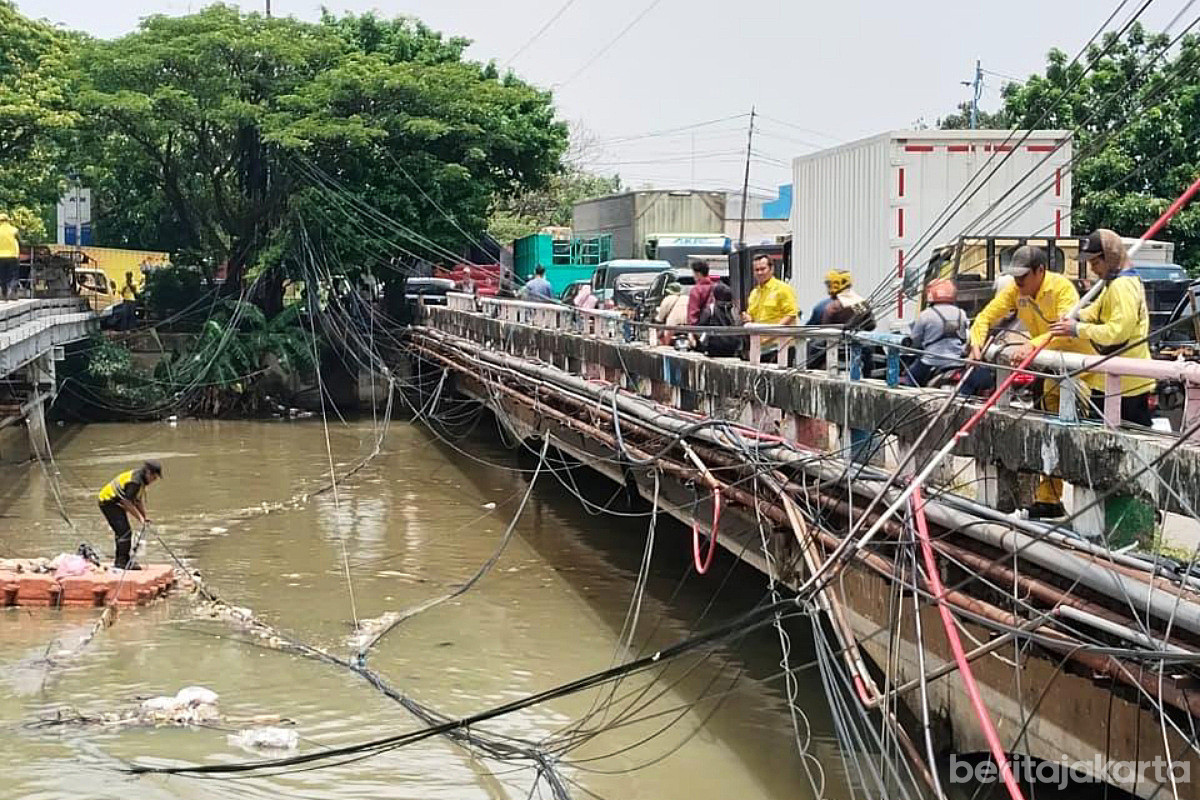 Sejumlah petugas merapihkan kabel udara semrawut yang berada di Jembatan Kapuk Pasar Darurat