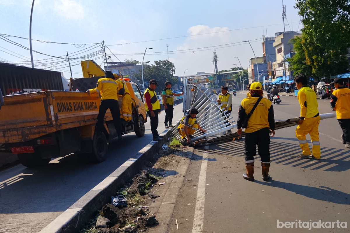 Sejumlah petugas sedang mengangkat pagar rusak akibat aksi demo