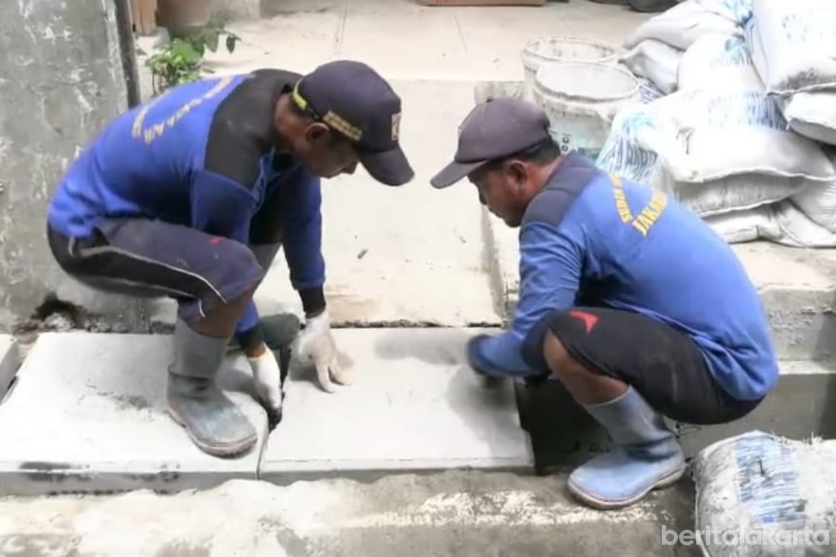 Petugas melakukan pemasangan tutup saluran di Jalan Manggis II