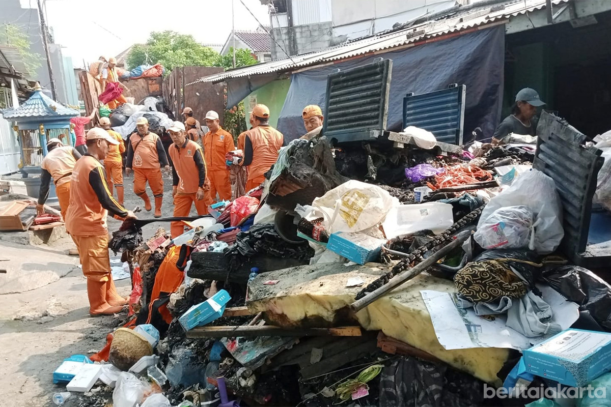 Petugas PPSU bersama warga mengangkut puing sisa kebakaran di Jalan Kelapa Tunggal