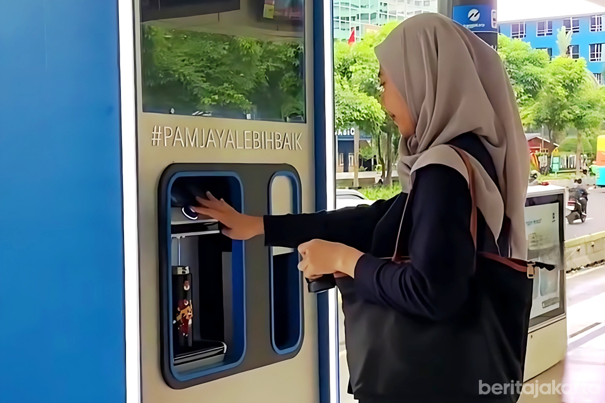 Penumpang mengisi botol air dari water refill station di halte transjakarta