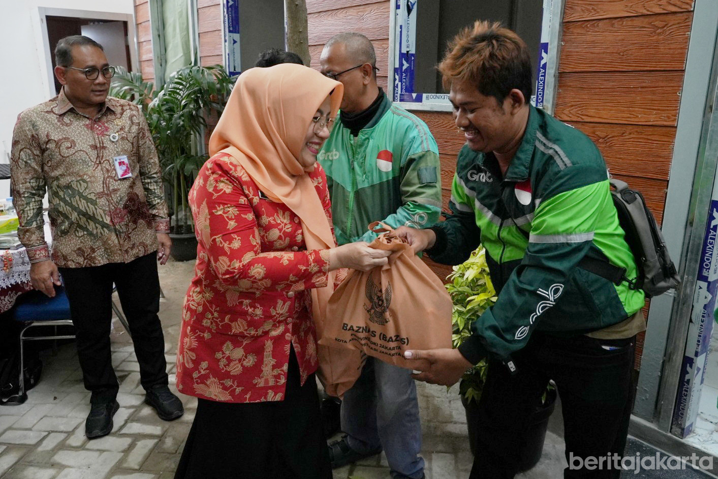 https://multimedia.beritajakarta.id/photo/2014_508c75c8507a2ae5223dfd2faeb98122/Ketua DWP Jakpus, Witri Yenny Arifin memberikan paket sembako ke salah satu pengemudi ojek online
