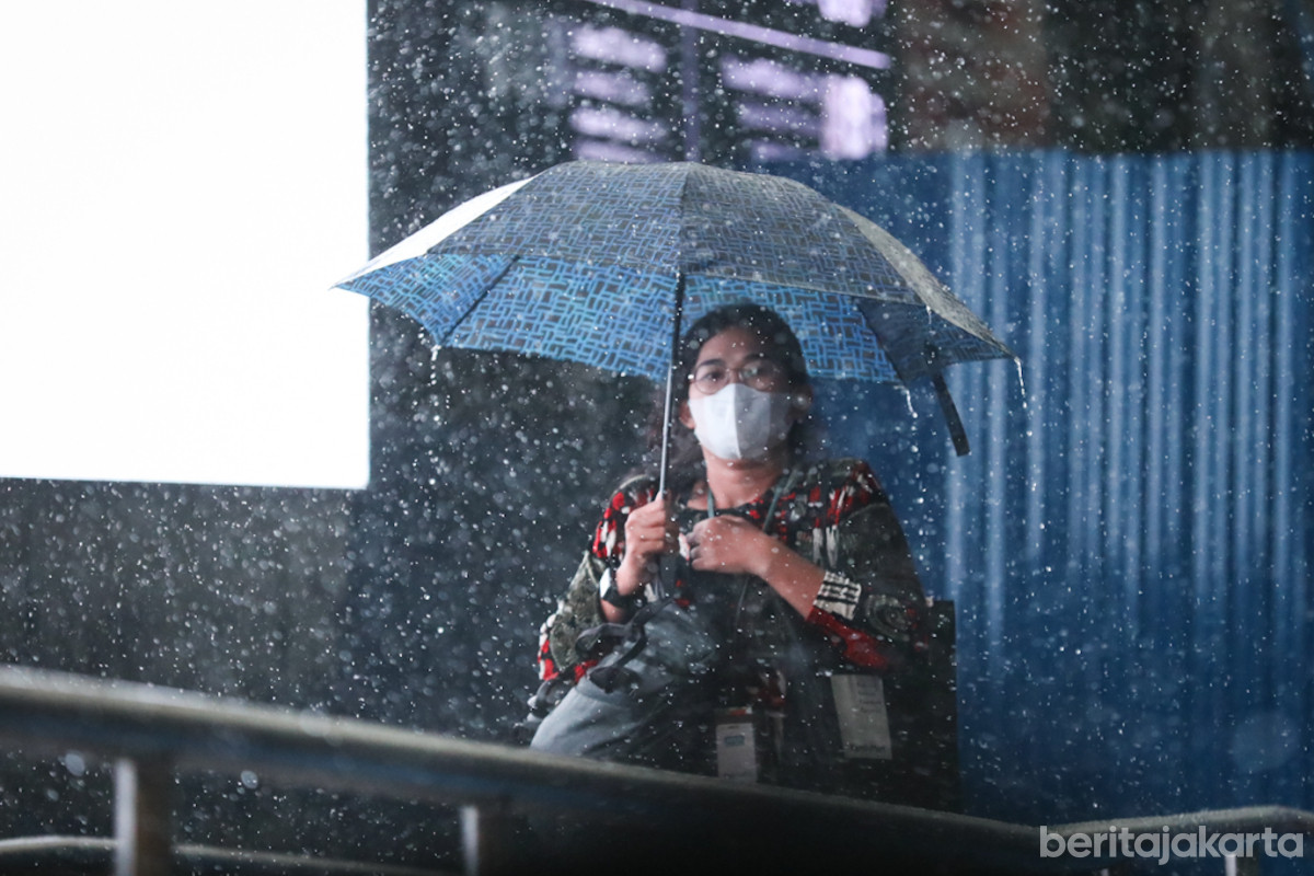 Seorang warga menggunakan payung saat hujan basahi Jakarta