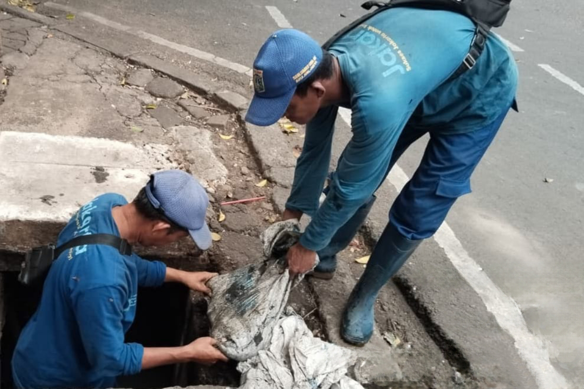 Petugas sedang menguras saluran air di Jalan Awaludin IV