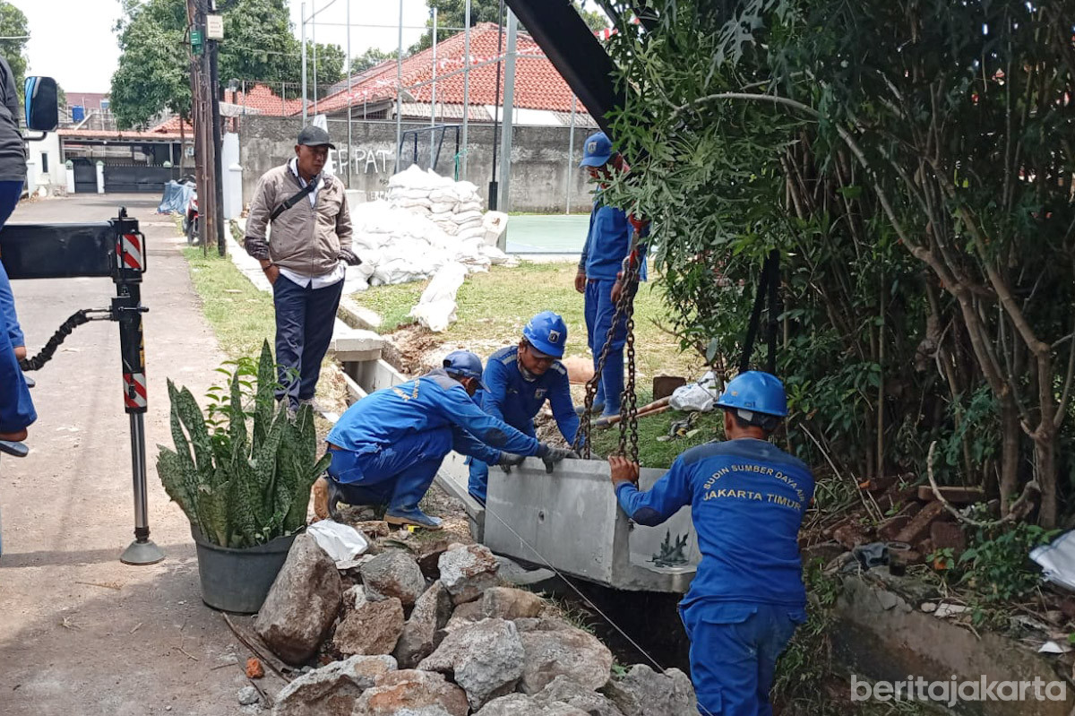 Sejumlah petugas SDA menurunkan u-ditch saluran air di Kelapa Dua Wetan