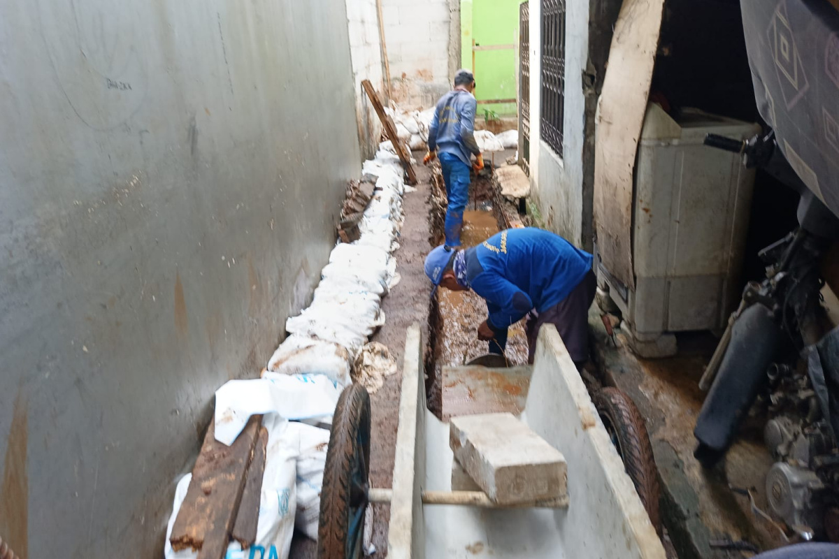 Pekerja melakukan pemasangan beton U-ditch ke dalam saluran