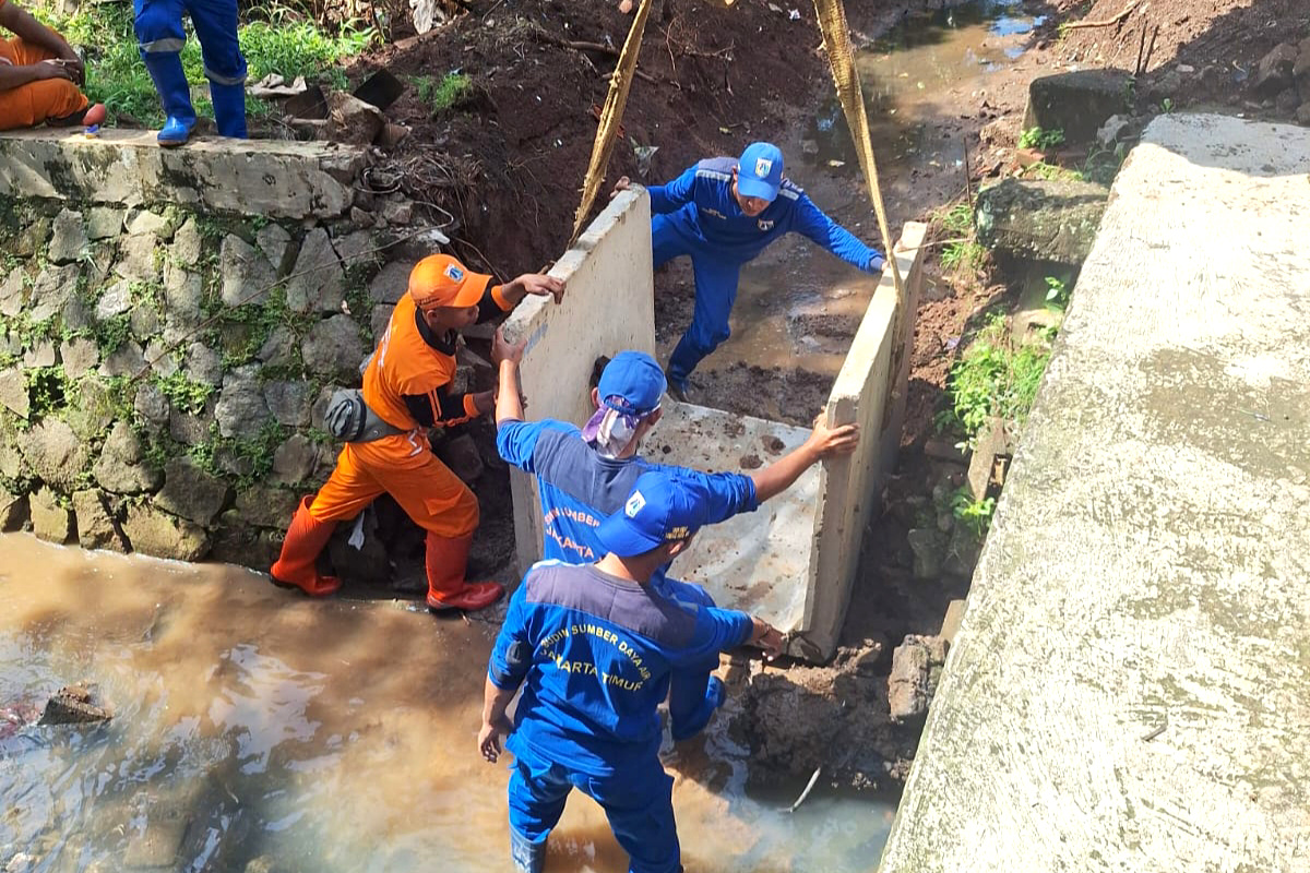 Proses pemasangan beton u-ditch ke dalam saluran air di Lubang Buaya