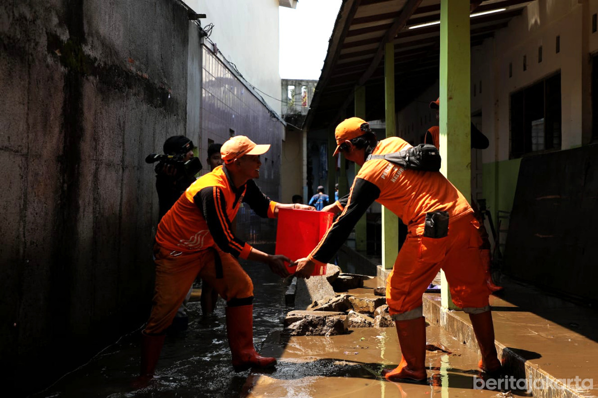 Petugas PPSU bahu membahu membersihkan lingkungan rumah warga pascagenangan di Jati Padang