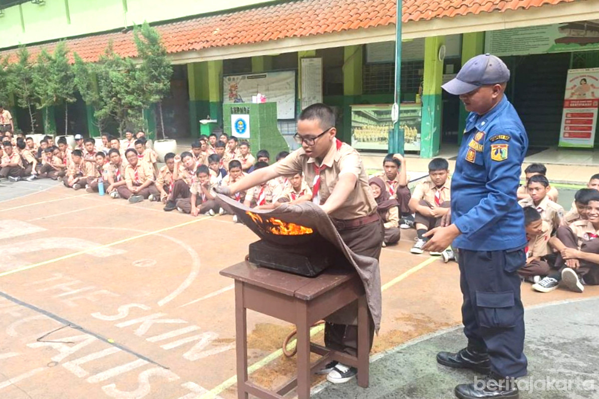 Seorang Pelajar sedang melakukan pemadaman api dengan kain goni