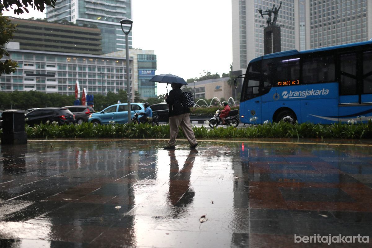 https://multimedia.beritajakarta.id/photo/2014_508c75c8507a2ae5223dfd2faeb98122/Seorang warga menggunakan payung berjalan di kawasan Bundaran HI