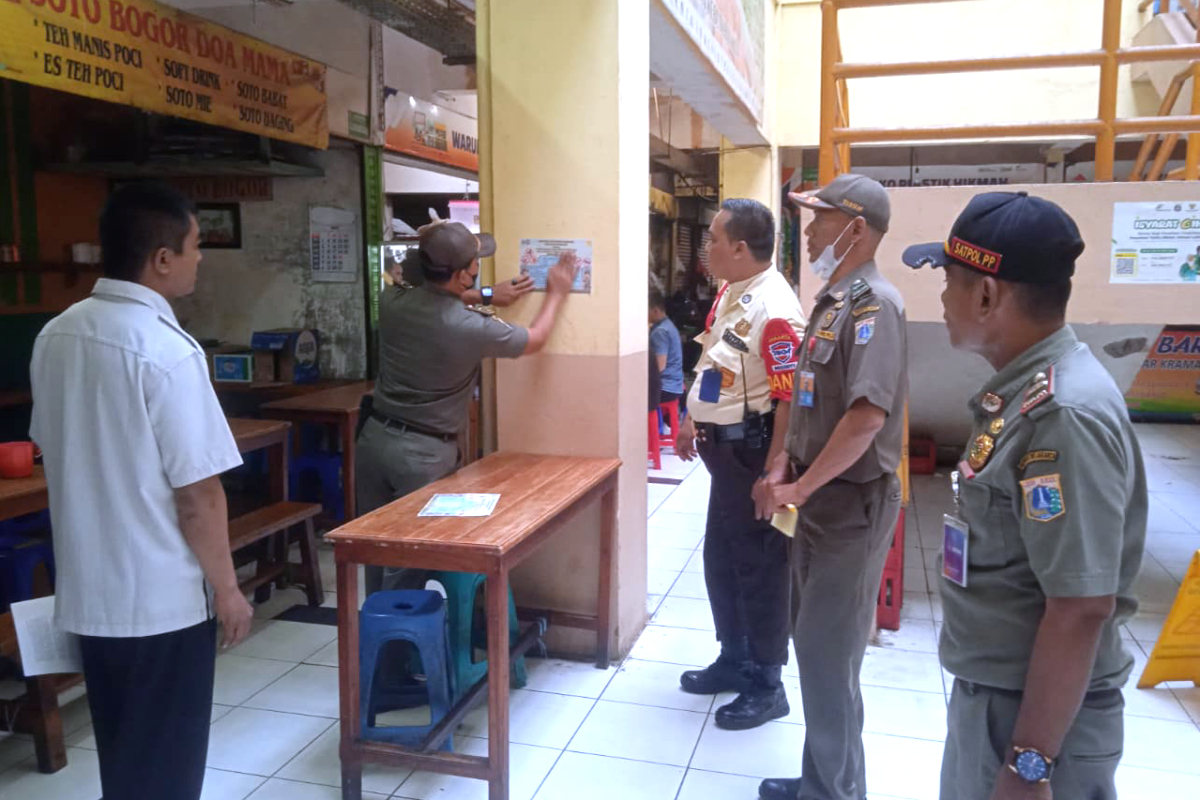 Petugas Satpol PP melakukan sosialisasi dan menempelkan stiker Pergub No.36 Tahun 2025 di Cililitan