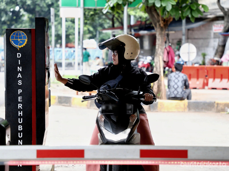 Pengendara motor mengambil tiket parkir di gate otomatis