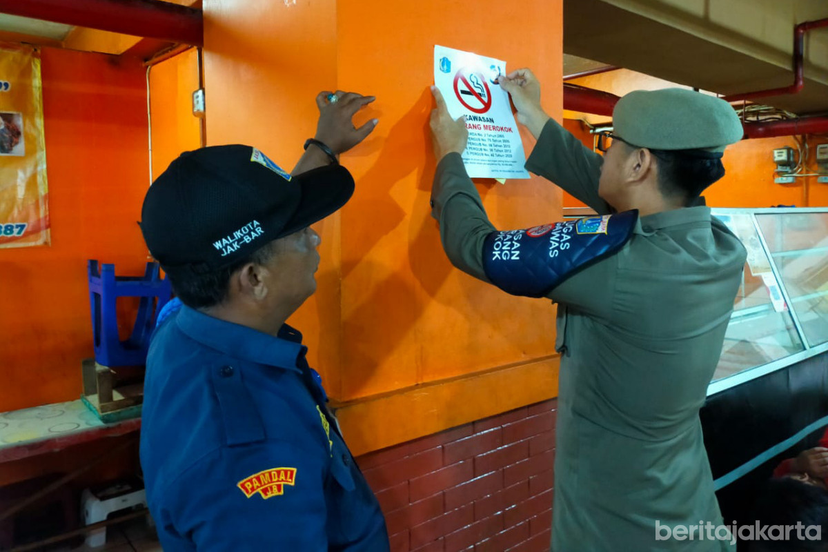 Petugas sedang menempelkan stiker dilarang merokok di kantin Wali Kota Jakarta Barat