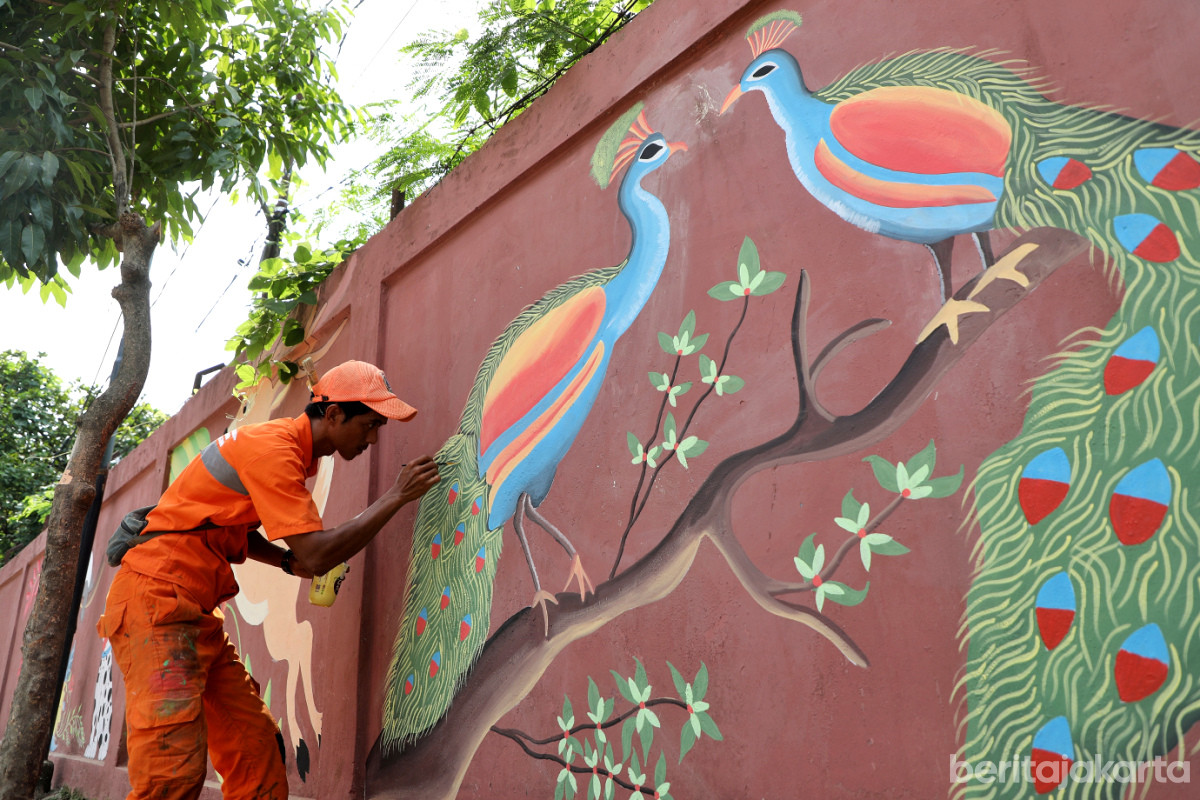 Seorang petugas sedang menyelesaikan pembuatan mural burung merak